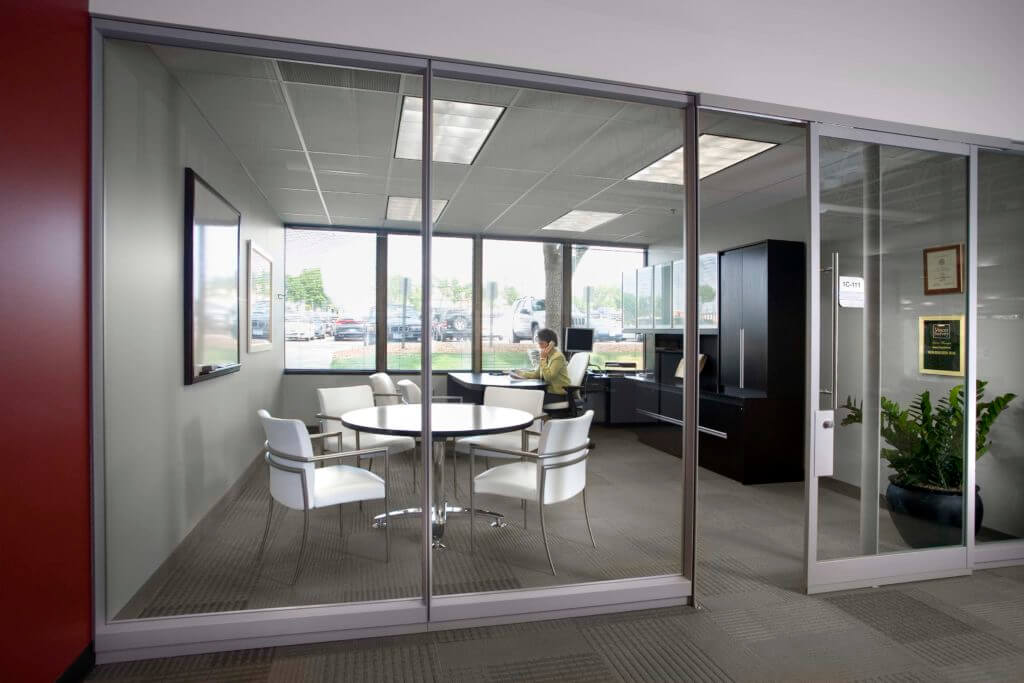 Woman working at desk in office seen through glass wall
